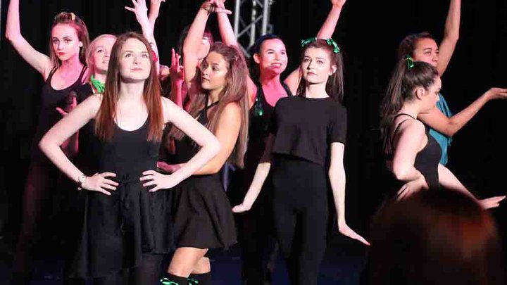 Female students dressed in black dresses dancing