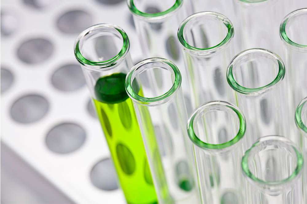 A row of clear test tubes with one full of a green liquid