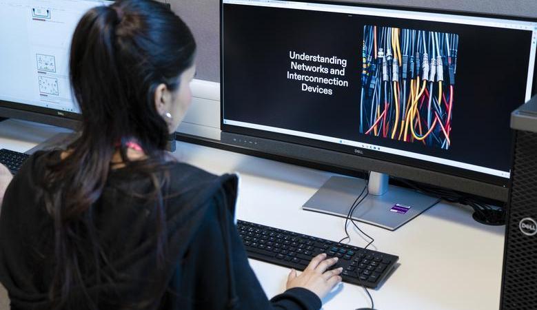 Photograph of a student sat at a computer in a classroom setting.