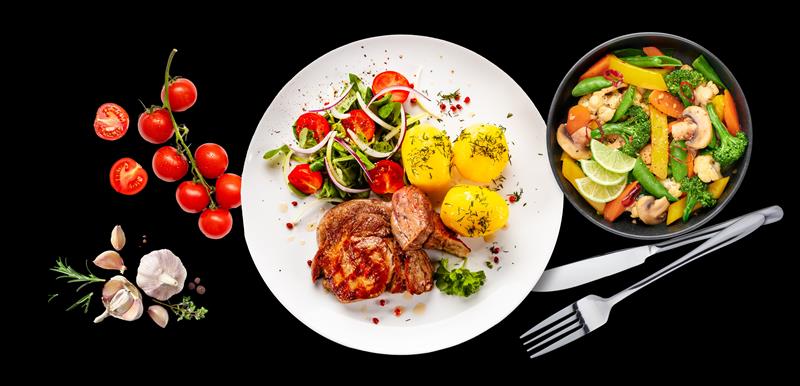 Freshly prepared meals on plates against a black background