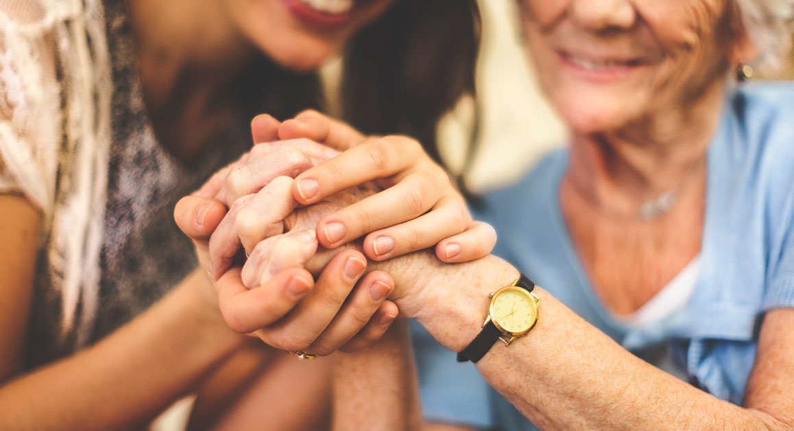 A carer holding a woman's hand