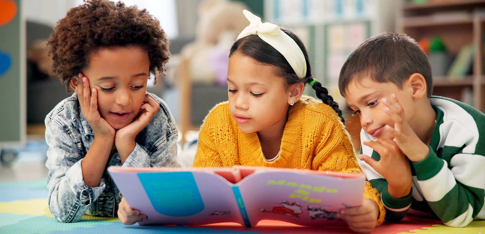 Three children sat together reading a book