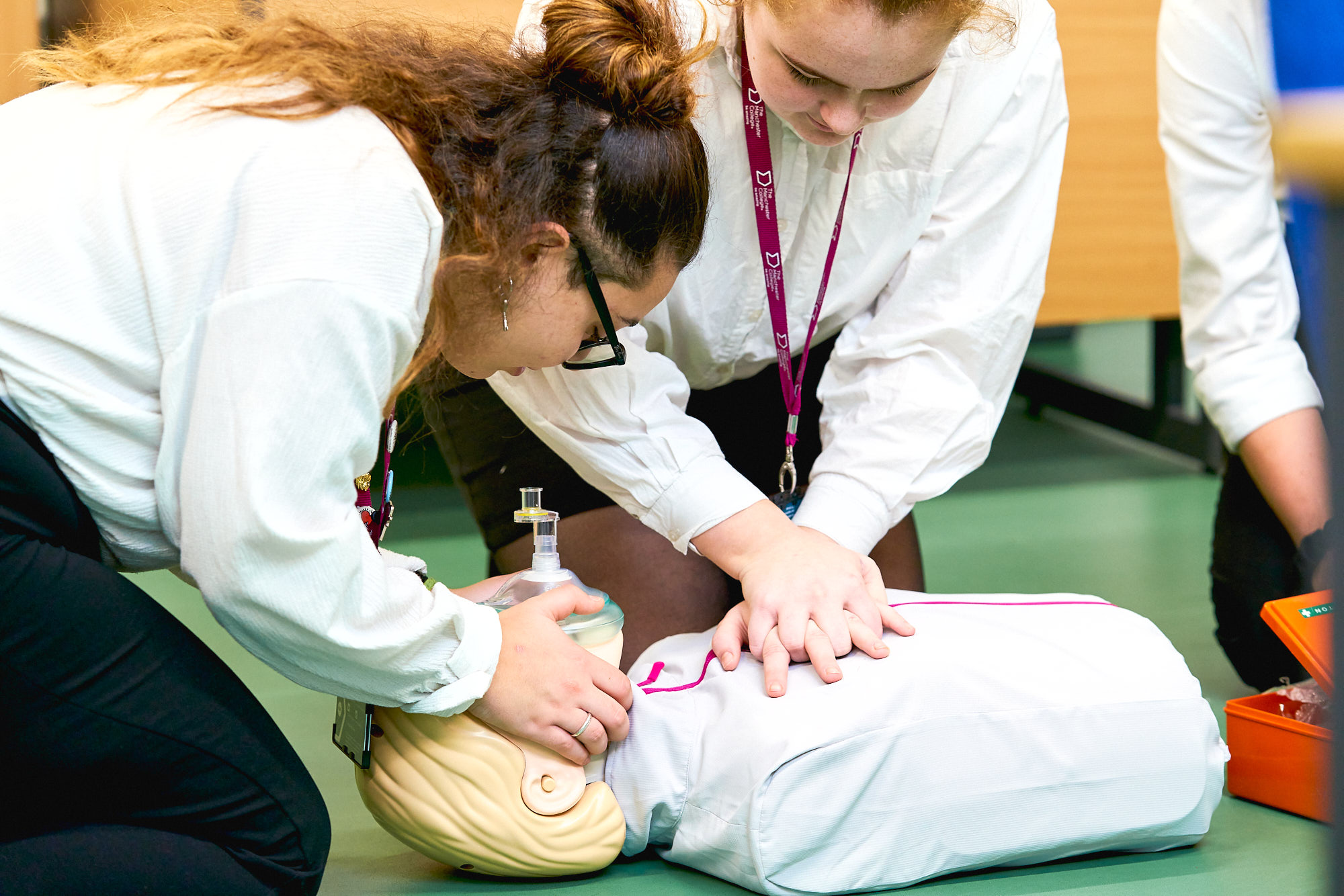 Students practice CPR on training manikin