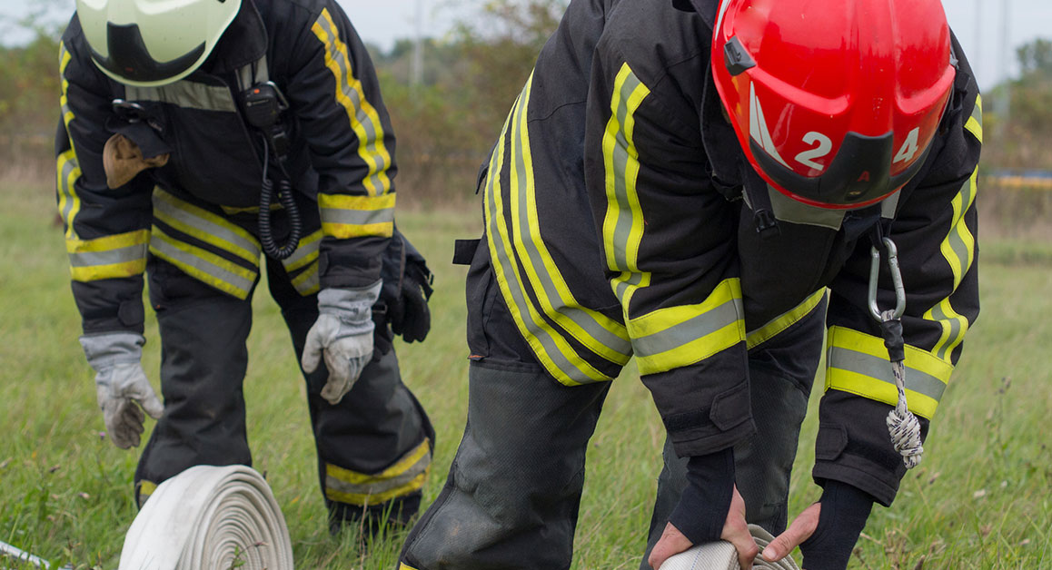 Two firefighters rolling out a hose