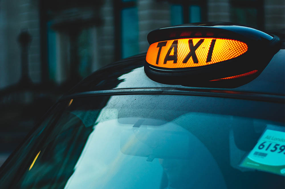 A lit up Taxi sign on a car