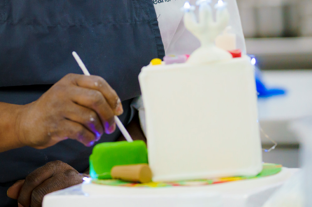 A student decorating a castle shaped cake