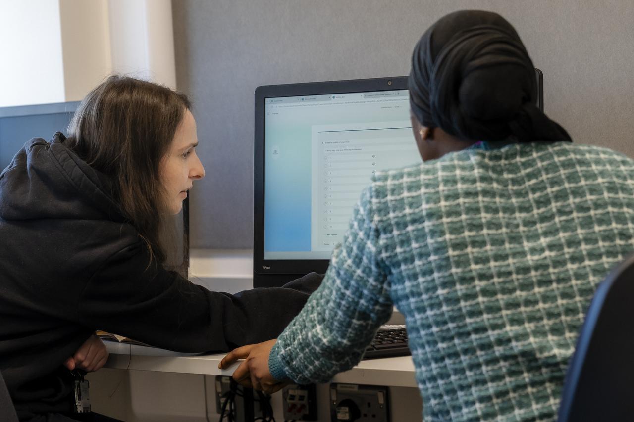 Two TMC students collaborate at a computer workstation, reviewing information on screen together while completing a task in a classroom setting.