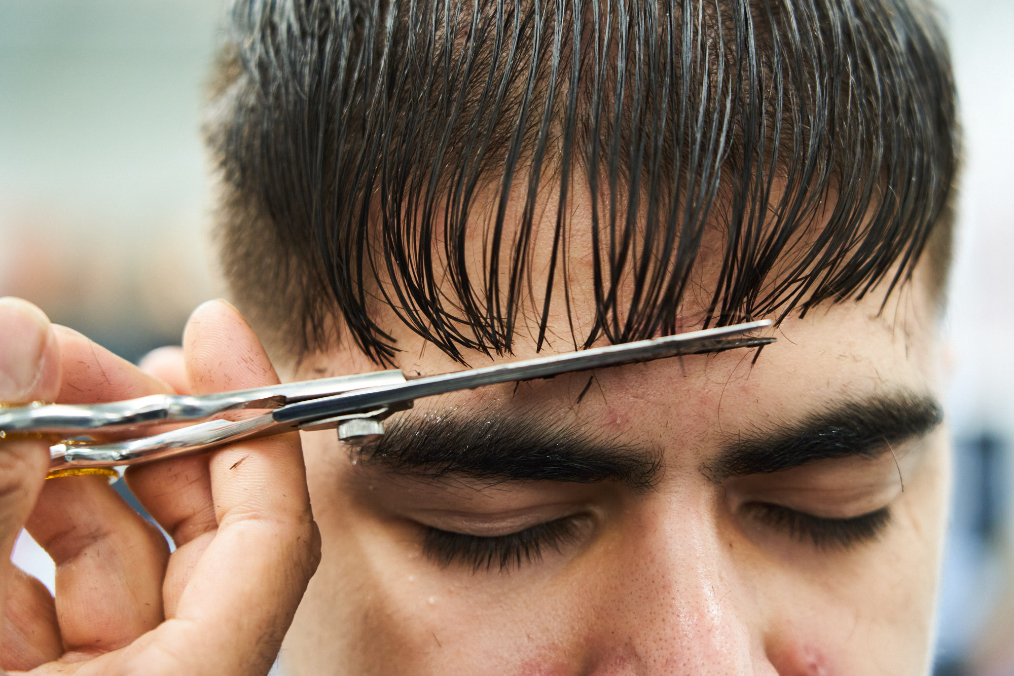 Close up of a man getting his haircut with scissors