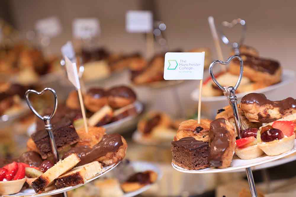 Selection of freshly made cakes with a Manchester College flag sticking out