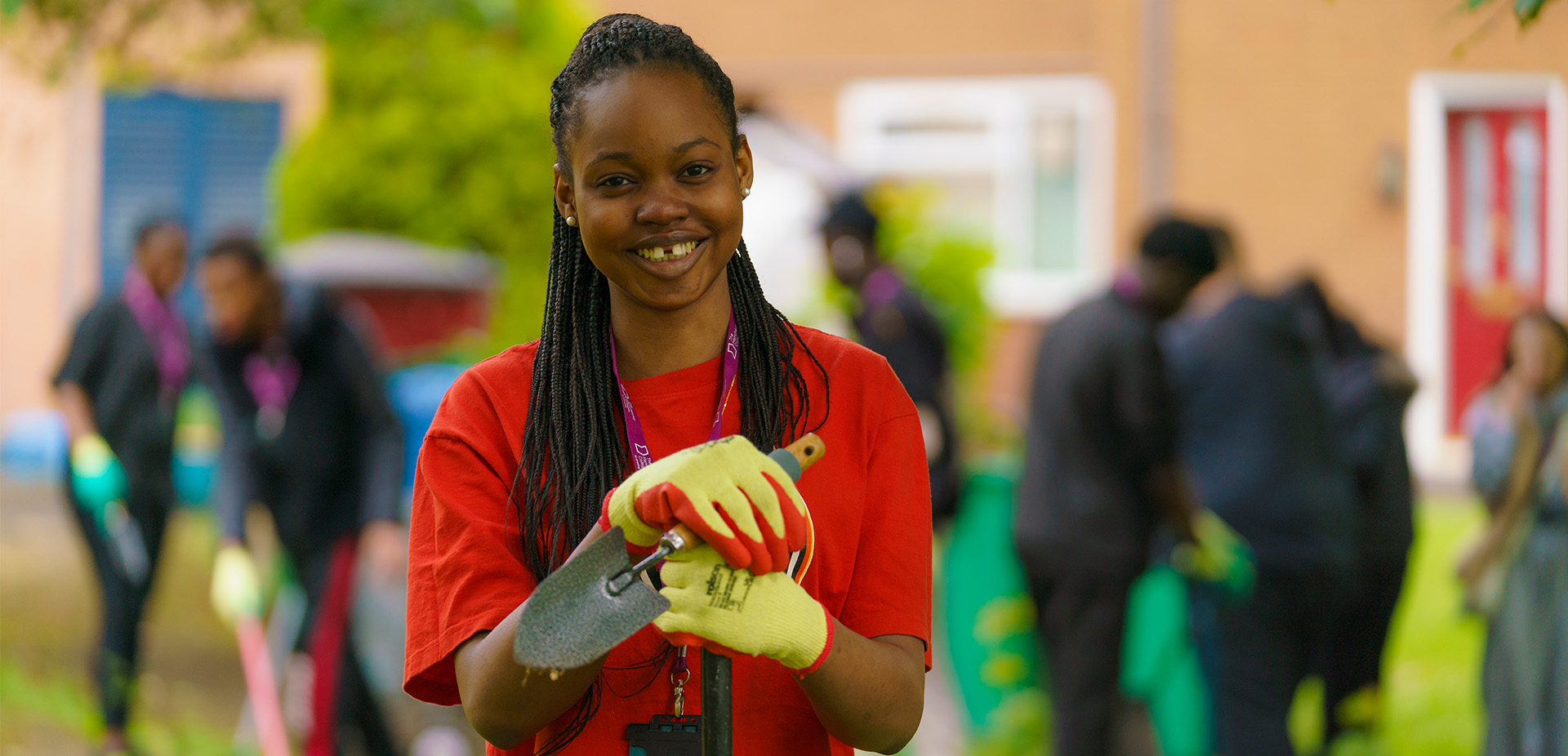 Portrait image of a learner smiling at the camera while holding a garden trowel