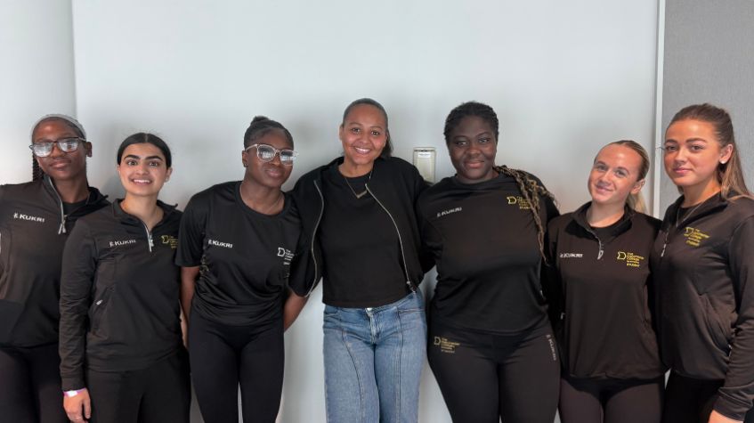The Manchester College Sport students at the Women in Sport Conference, in front of a white wall.