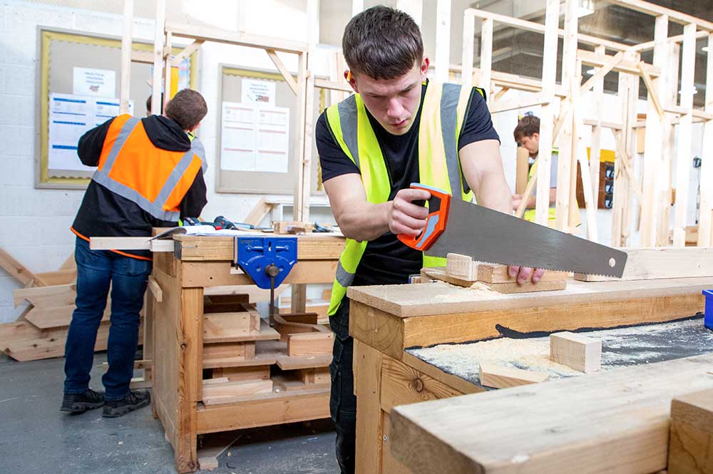 Student carpenter cutting a plank of wood