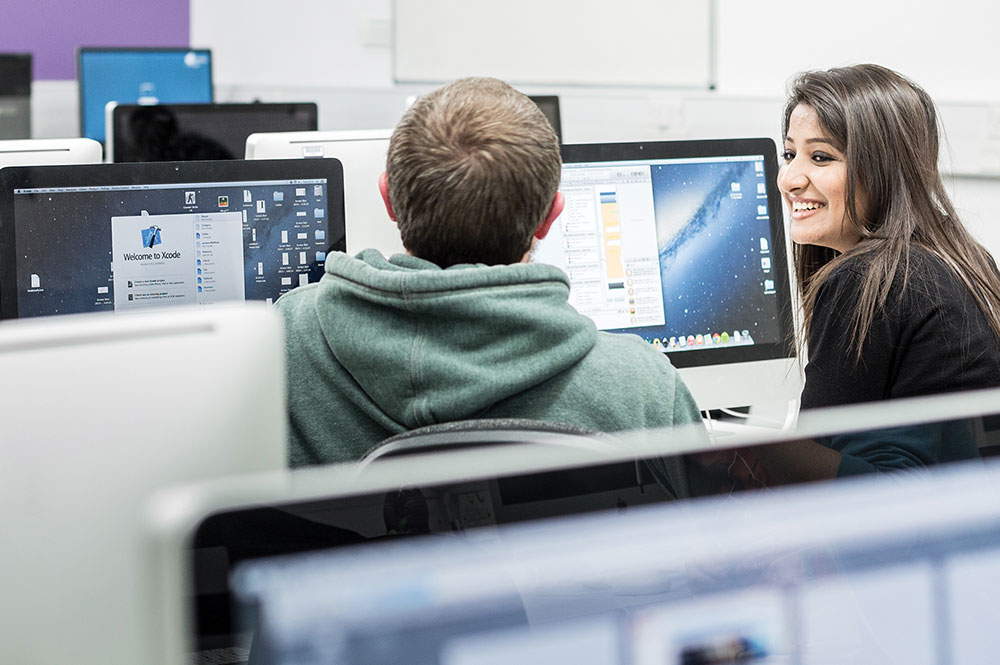 Two students sat at a bank of computers