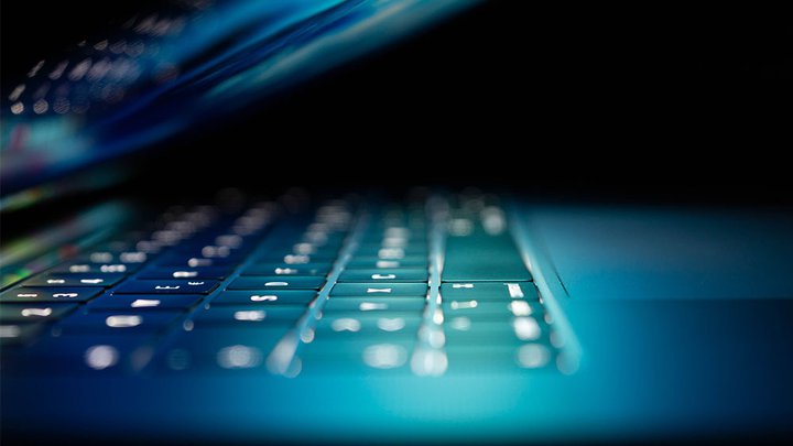 Close-up of a laptop partially closed with a colourful screen