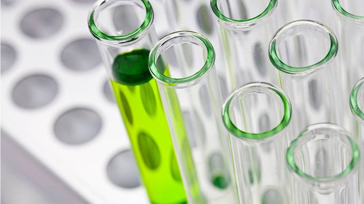 A row of clear test tubes with one full of a green liquid