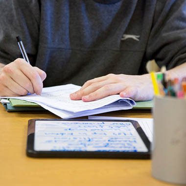 Student writing at a desk