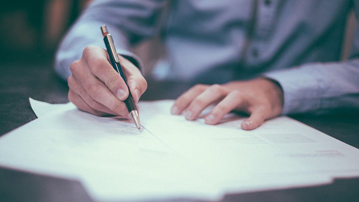 Close-up of someone signing contracts