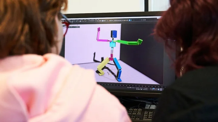 Two learners working on a 3D animation project, viewing and adjusting a colourful motion‑capture character model on a computer screen in a creative and digital media classroom.