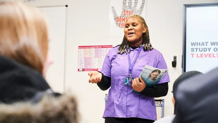 A health and social care learner delivering a classroom presentation while holding a course booklet.