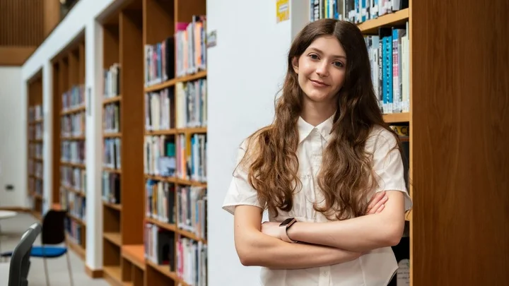 Learning space showing a person standing in a library study area with bookshelves and individual work seating.