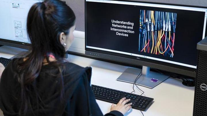 Photograph of a student sat at a computer in a classroom setting.