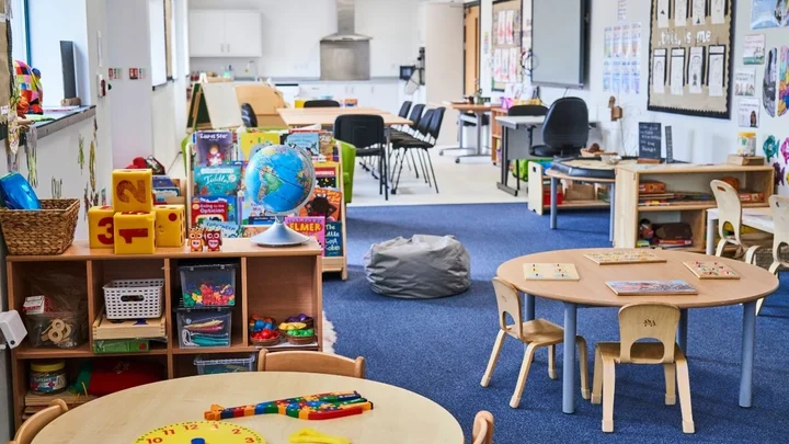 A colourful early years classroom with play tables, learning resources and activity stations.