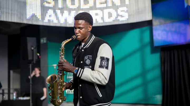 Music student playing a saxophone on stage during a live performance event at The Manchester College Student Awards
