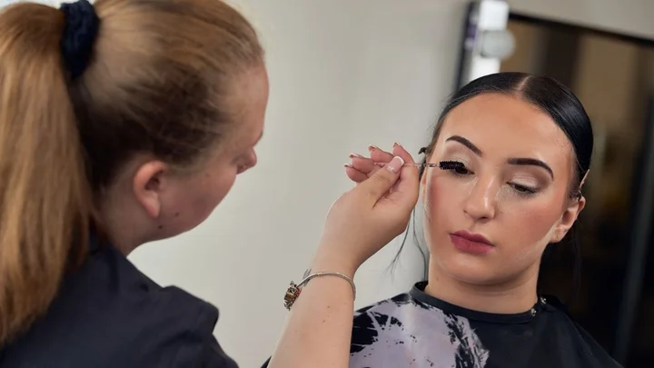 A makeup student practising eyebrow shaping during a theatrical and media makeup training session.