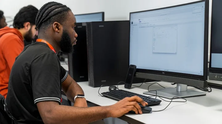 Person using a desktop computer and mouse to work through on‑screen tasks during a classroom learning session.