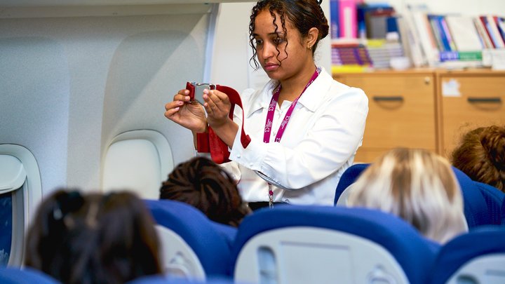 Student conducting a safety briefing in mock air cabin
