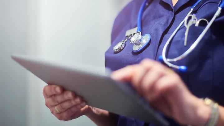 A healthcare professional writing on a clipboard