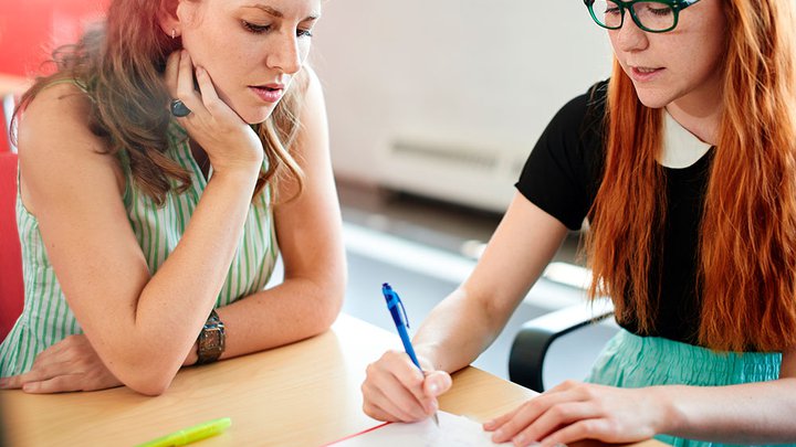 Two women sat together with one lady assessing the others piece of work