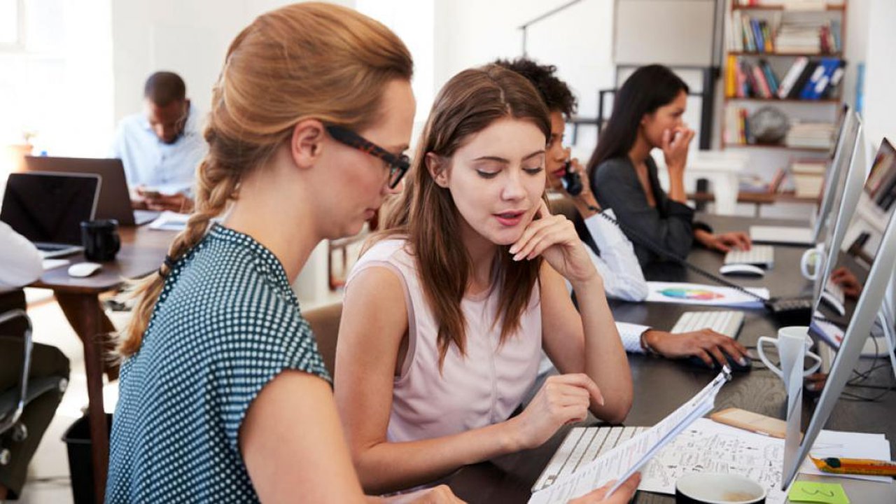 Two women sitting at a computer in an office