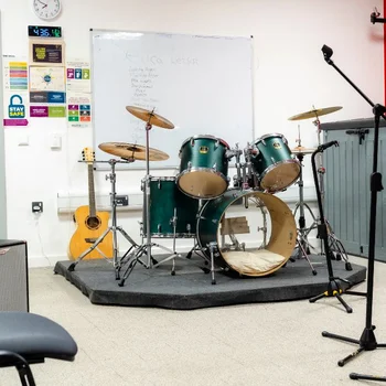 Band rehearsal studio at The Manchester College City Campus Manchester, featuring a drum kit, guitars, amplifiers and microphone stands.