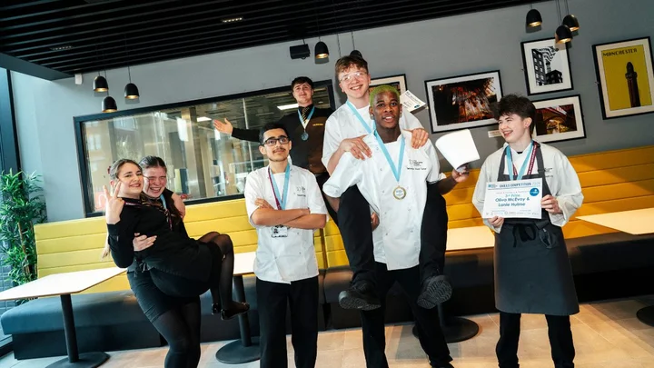 Hospitality and Catering students displaying competition certificates and medals in a college restaurant training environment.
