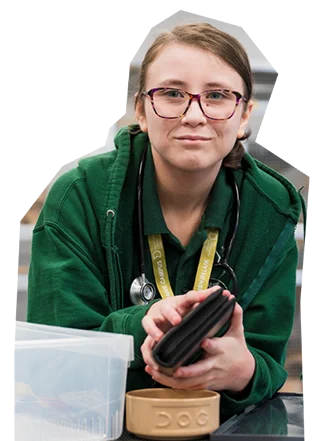 College learner wearing glasses and a green hoodie, holding a case with a stethoscope around their neck, shown as a cut-out image.