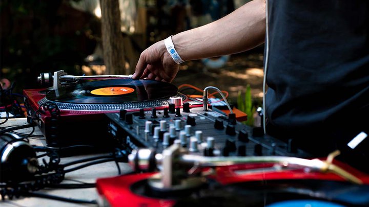 A man in a black shirt stood next to a DJ set-up