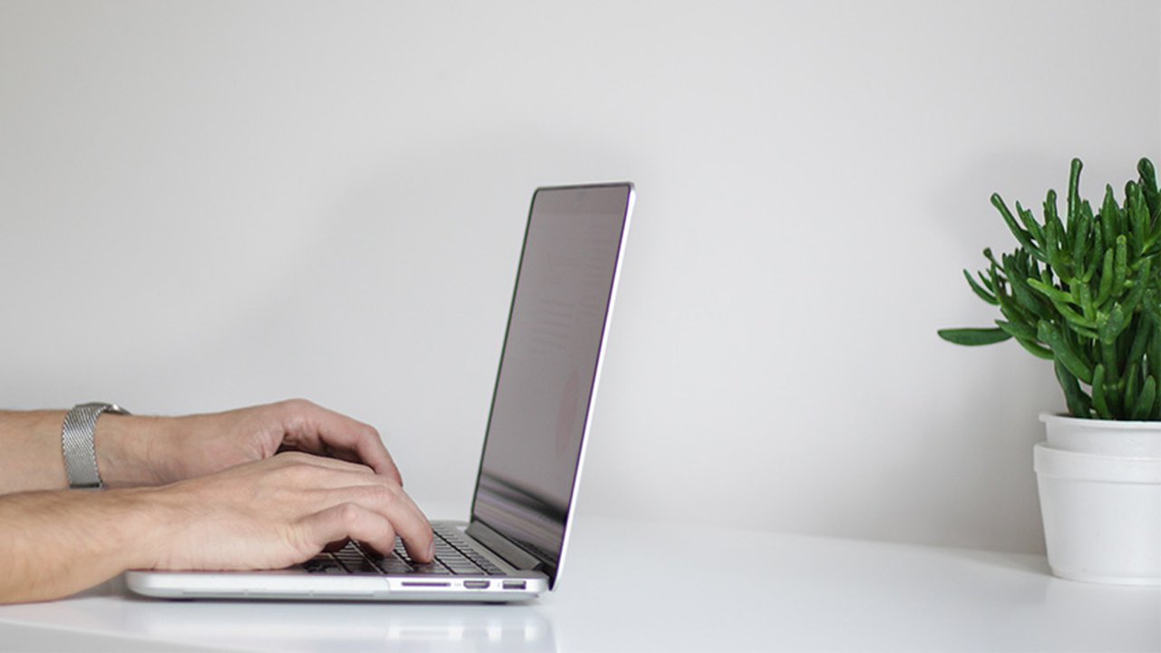 Hands typing on a laptop