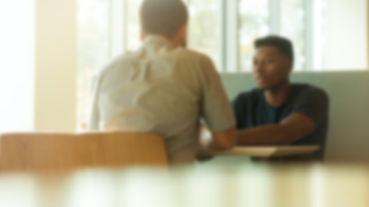 Two people talking to each other over a table