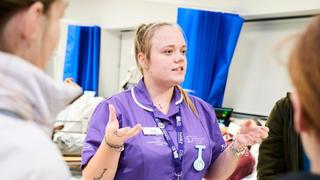 Health and social care student at The Manchester College talking to prospective students during an open event.