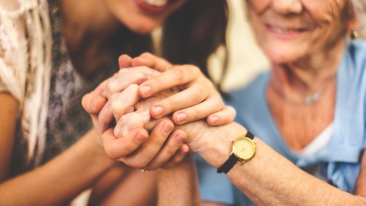 A carer holding a woman's hand