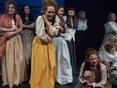 Female students performing in costume with some holding babies