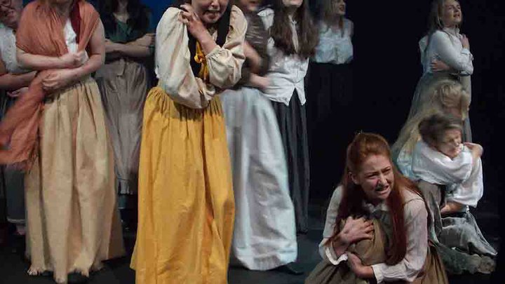 Female students performing in costume with some holding babies