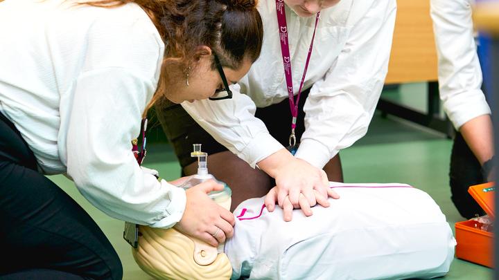 Students practice CPR on training manikin