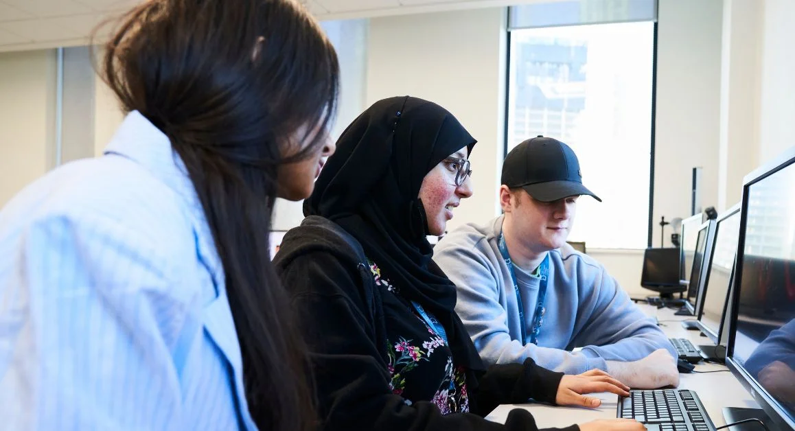 Three students looking at a computer screen together