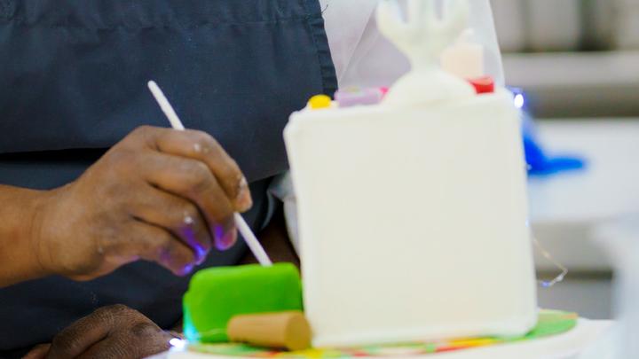 A student decorating a castle shaped cake