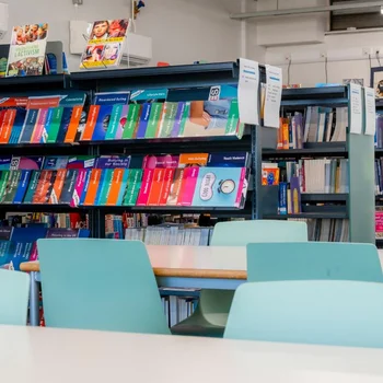Library at The Manchester College Harpurhey Campus with shelves of books and study tables.