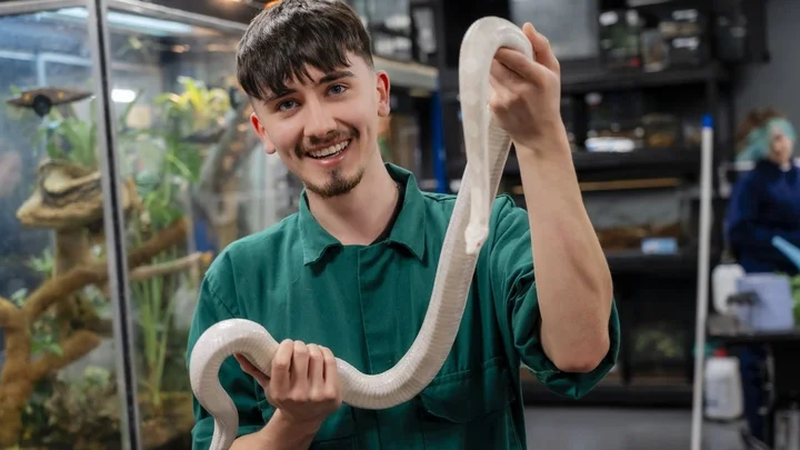 Animal Management practical session showing a learner holding a large pale‑coloured snake.