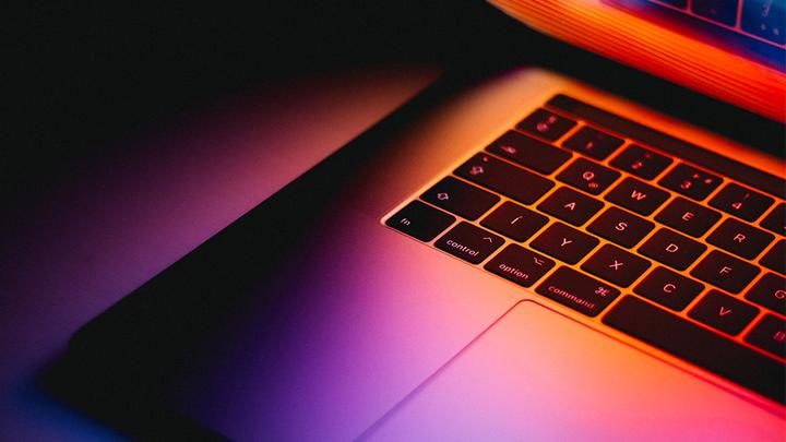Close-up of a laptop partially closed with a colourful screen