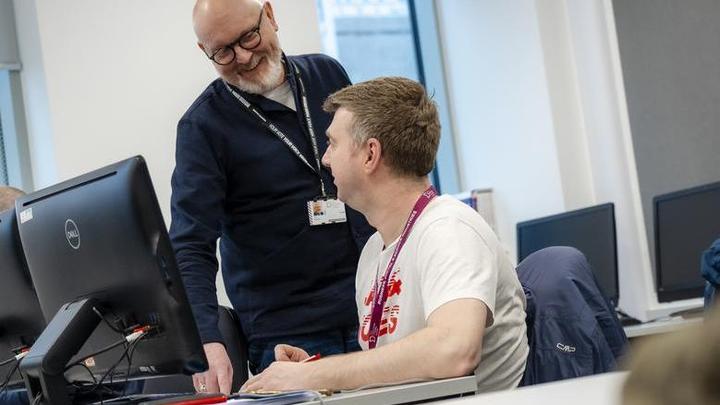 Photograph of a member of staff and student in conversation in a classroom setting.